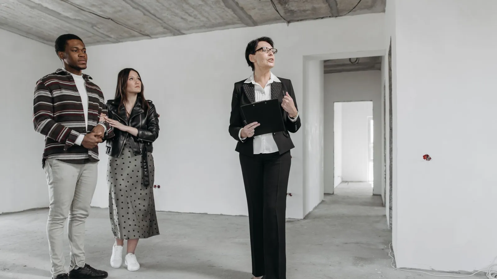 Boş inşaat halindeki dairede müşteriler ve emlak danışmanı incelemede