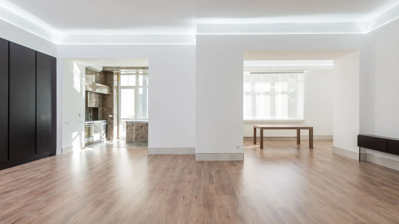 Ahşap zeminli, boş geniş salon ve mutfak girişi olan kiralık ev
